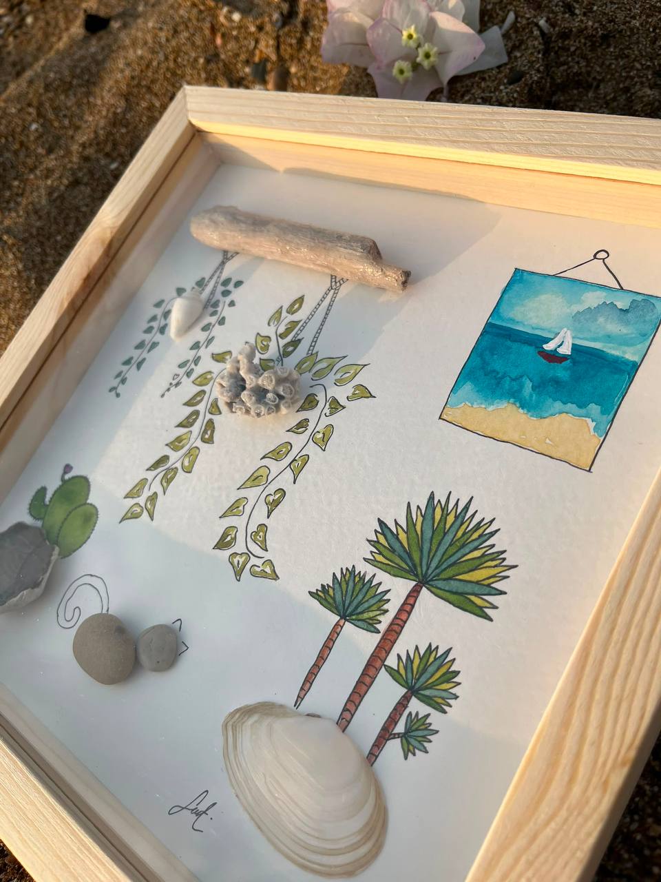 Two framed botanical shell artworks hanging among green plants